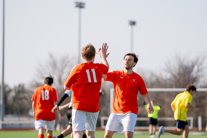Two players in orange high-five after a goal