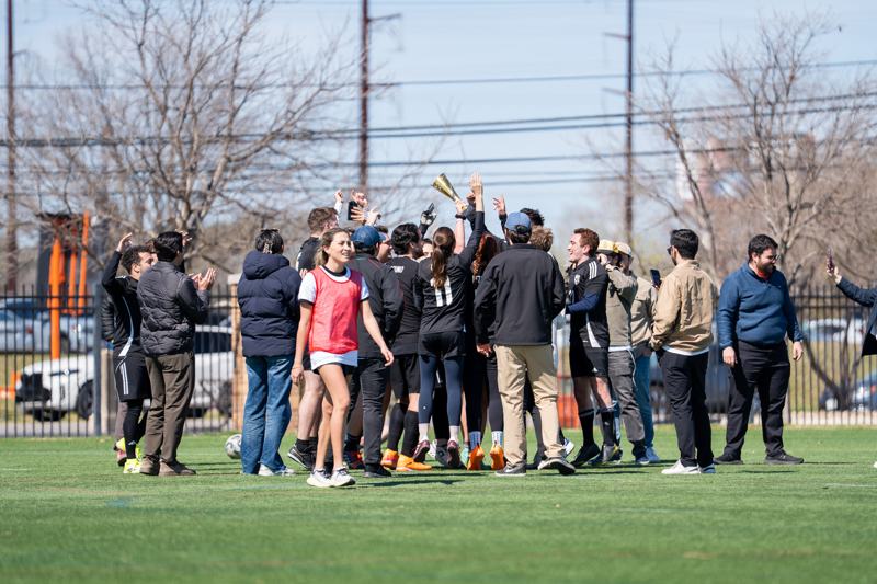 A team raises the trophy surrounded by supporters